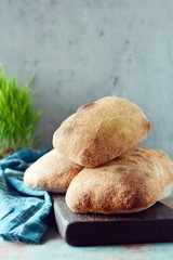 Freshly baked Italian ciabatta bread on wooden cutting board. Top view