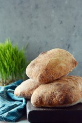 Freshly baked Italian ciabatta bread on wooden cutting board. Top view