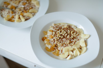 Bowl of oatmeal porridge with banana, blueberries, almonds, coconut and caramel sauce on teal rustic table, hot and healthy food for Breakfast, top view, flat lay