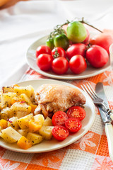 Baked chicken thigh with baked potatoes and pumpkin garnish on a plate