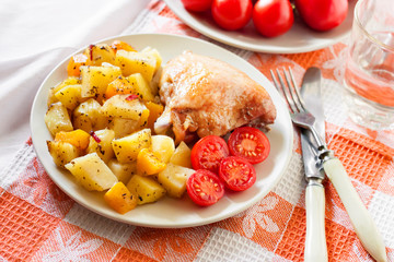 Baked chicken thigh with baked potatoes and pumpkin garnish on a plate