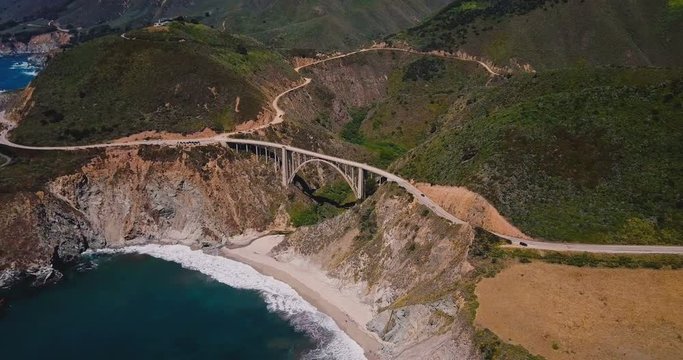 Drone zooming in on incredible Bixby Canyon Bridge and Highway 1 epic summer landscape panorama in Big Sur California.