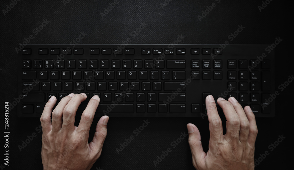Poster top view, hand typing computer keyboard on black background