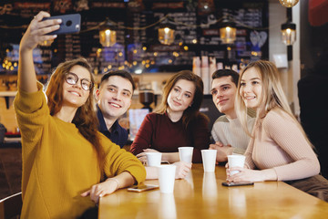 Five young handsome students sitting in a cafe.