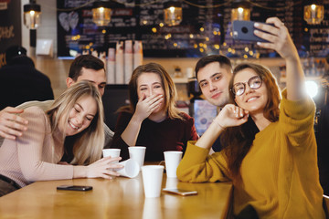 Five young handsome students sitting in a cafe.