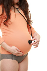 お腹に聴診器をあてるオレンジ色のシャツを着た臨月の妊婦