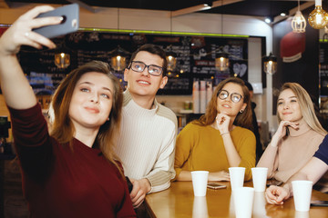 Five young handsome students sitting in a cafe.