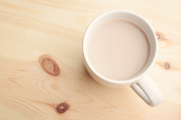 Hot chocolate with milk in cup on wooden background in kitchen. Breakfast drink