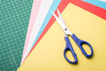 Blue scissors on coloured papers. Modeling with paper