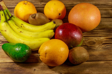 Assortment of tropical fruits on wooden table. Still life with bananas, mango, oranges, avocado, grapefruit and kiwi fruits