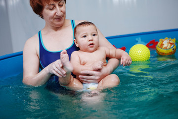 Mother with baby exercises in the pool.
