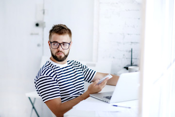 Young business man,  sitting at desk at home and looking at open laptop display.