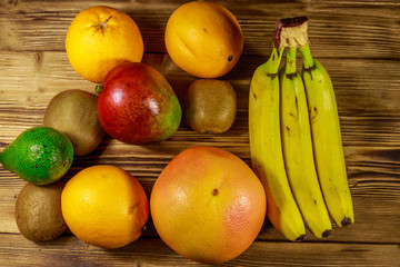 Assortment of tropical fruits on wooden table. Still life with bananas, mango, oranges, avocado, grapefruit and kiwi fruits