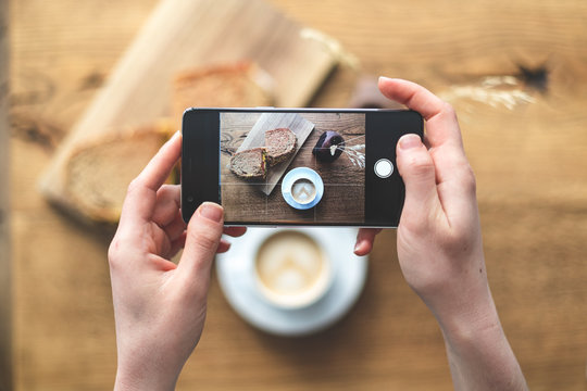 Woman making photo of her breakfast coffee and sandwich on cellular