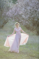 Fototapeta na wymiar Beautiful girl wearing a bridal gown in a pink forest