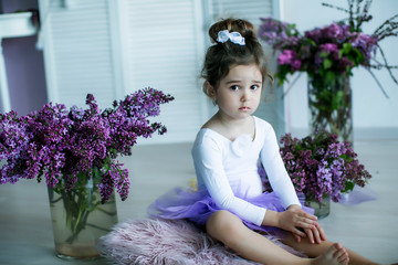 Adorable little girl dressed as a ballerina in a tutu, tying her ballet slippers. © ElenaBatkova