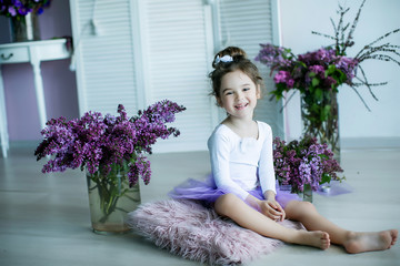 Adorable little girl dressed as a ballerina in a tutu, tying her ballet slippers. © ElenaBatkova