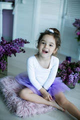 Adorable little girl dressed as a ballerina in a tutu, tying her ballet slippers.