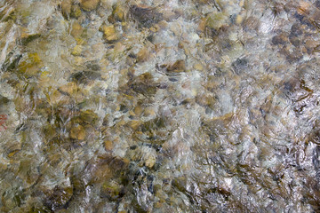 top view of pebble stones in fast-moving stream, abstract picture