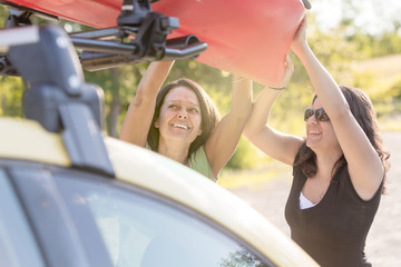 Mother and Daughter Teamwork loading Kayak on Car Roof Rack
