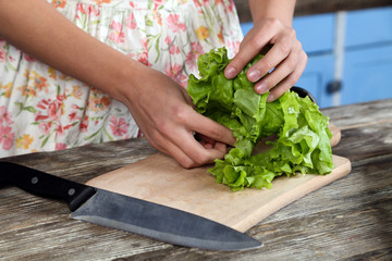 Girl  is cutting green salad with big knife