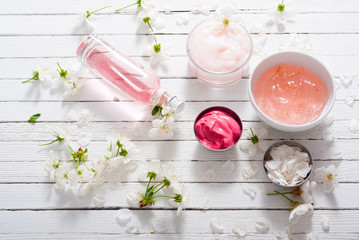 beauty products and cherry blossom on white wood table