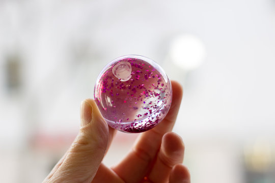 Kugel mit pinkem Glitter in der Hand