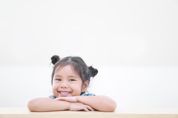Naklejka premium Asian children cute or kid girl and student thinking for new idea and happy fun or smiling white teeth on wood table at kindergarten classroom or nursery and child dental hospital or school on white