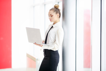 Business woman in a white blouse and a black skirt makes entries in a notebook at office center.