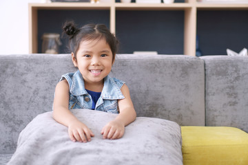 Fototapeta premium Asian child or kid girl and student thinking for new idea and happy fun or smiling white teeth with sit on sofa at kindergarten classroom or nursery and children dental hospital or home school