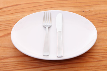 木製テーブルに置かれた白い皿とカトラリーによる食事終了の合図