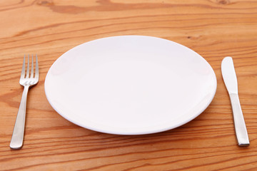木製テーブルに置かれた白い皿とカトラリー