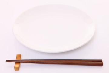 白いテーブルに置かれた白い皿と箸