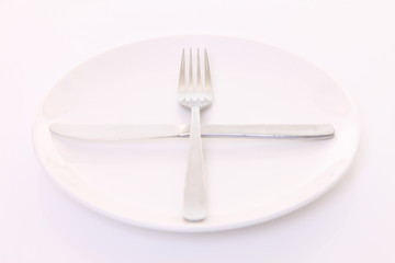 白いテーブルに置かれた白い皿とカトラリーによる次の料理を待機の合図