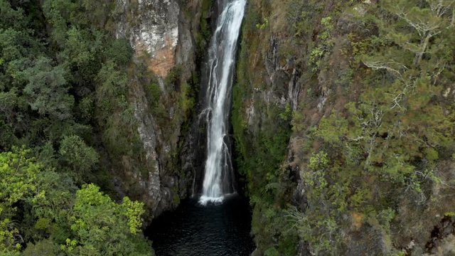 Aerial Tilt-up: Scenic Waterfall on Mossy Rocks Among Lush Green Forest