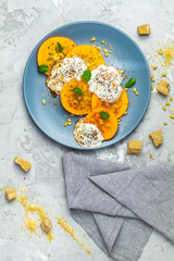 Sliced persimmon with yogurt, brown sugar, pine nuts and fresh mint
