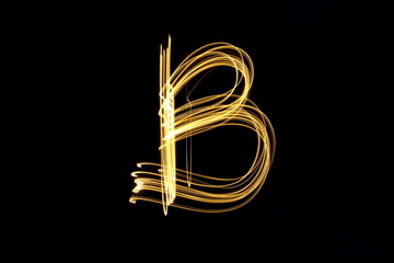 Long exposure, light painting photography.  Letter b in a vibrant neon metallic yellow gold colour against a black background.  Alphabet series.