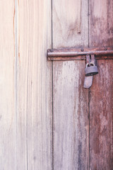 Old rusty steel latch with locked on wood door brown background