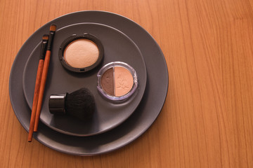 minimal concept background with make up, brushes and powders, on a grey plate, on a wooden table