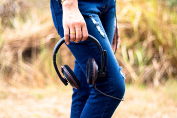 Woman standing holding in hand  black earphone.