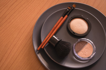 minimal concept background with make up, brushes and powders, on a grey plate, on a wooden table