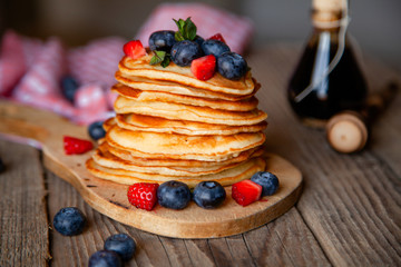 Pancakes with berries and maple syrup and sugar powder