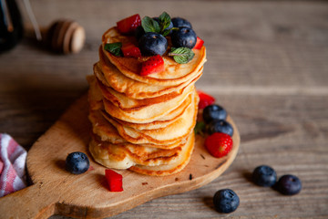 Pancakes with berries and maple syrup and sugar powder