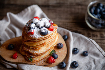 Pancakes with berries and maple syrup and sugar powder