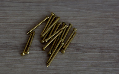 close up view of new brass nails, some brass nails on a wooden background as a contrast for nature and technology