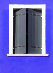 rectangular window with closed shutters and blue wall
