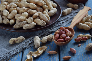 Peanuts in nutshell and peeled peanut on wooden background. Healthy and dietary nutrition. Raw food.