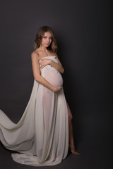 pregnant girl. pregnant on a dark background. pregnant in lingerie. a pregnant woman in the fabric