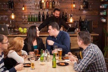 Happy friends group drinking beer and eating pizza at bar restaurant .