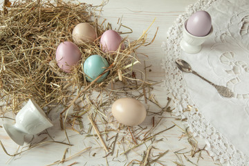 Fototapeta na wymiar Stack of colorful easter eggs on straw with wooden table background
